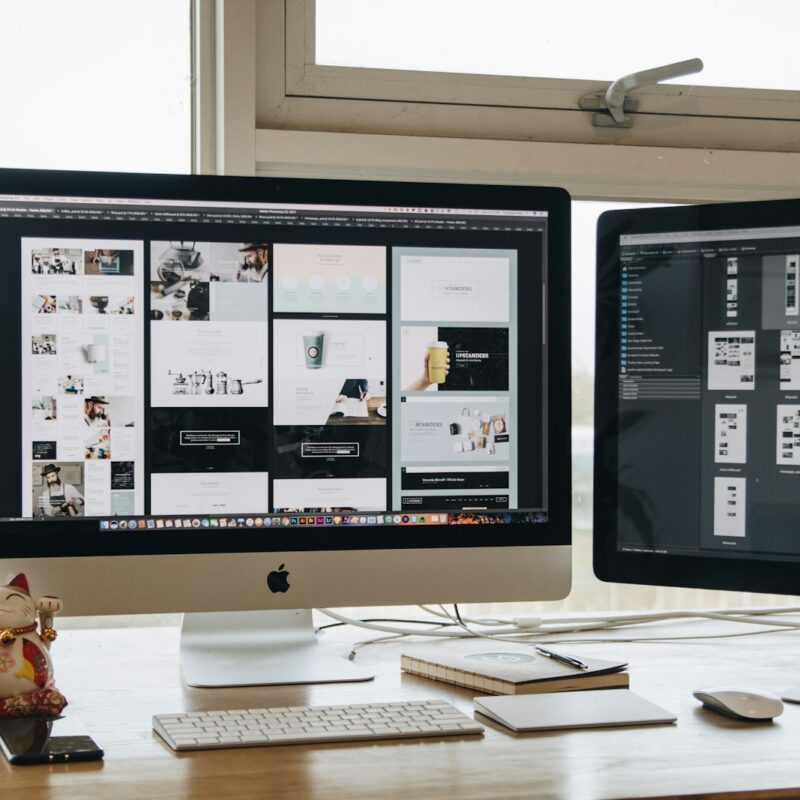 Two monitors setup next to each other on a computer desk.